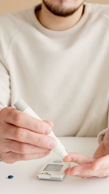 An adult using a blood glucose meter on a white surface for diabetes management.
